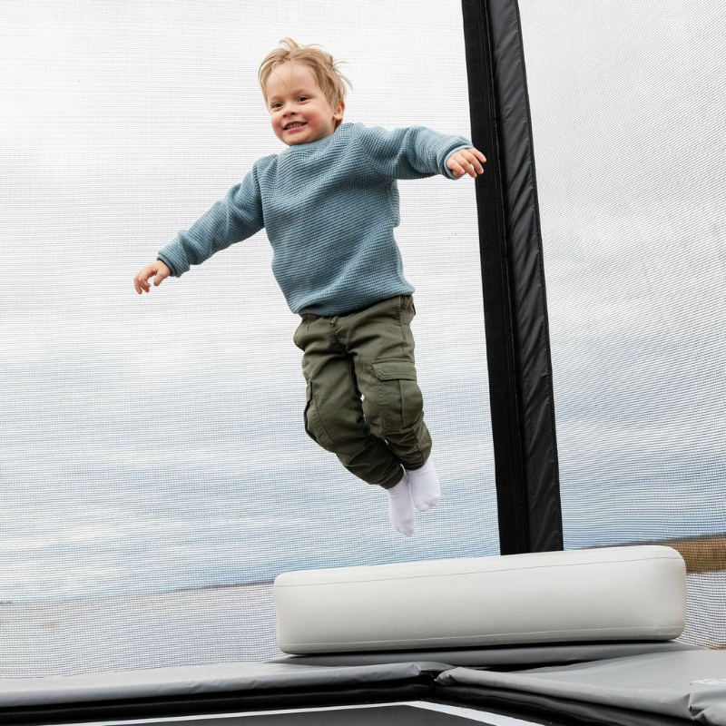 Child jumping on a trampoline using ACON X Block with a light blue sky in the background