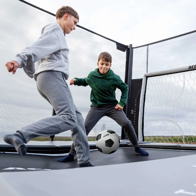 two young men playing soccer in Acon x trampolinem, they are using the ACON X Football Goal Panel
