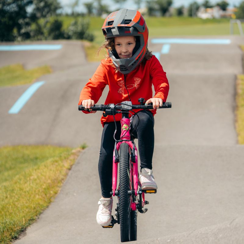 Child riding Frog 43 Bike on a paved path with a helmet on