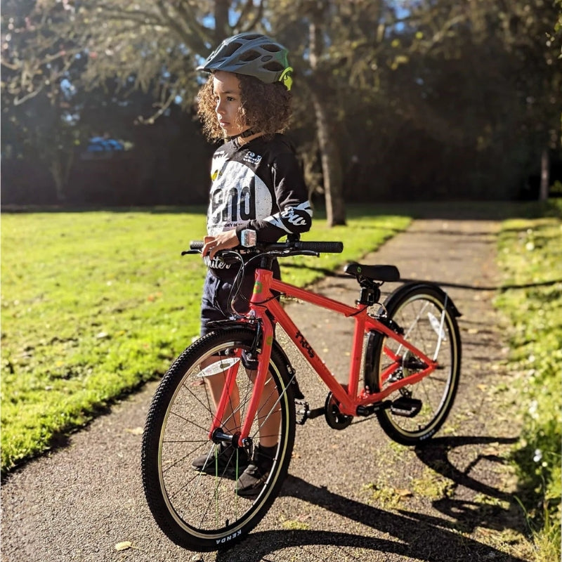 Child with a red bicycle on a path in a park