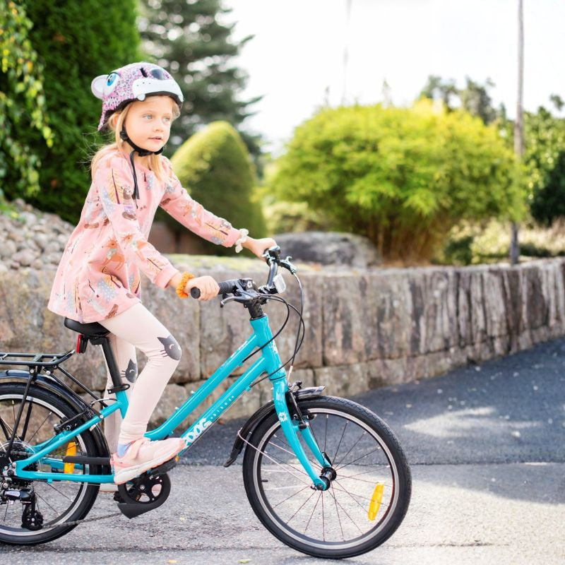 Child riding a city 53 teal bicycle on a paved path with greenery in the background