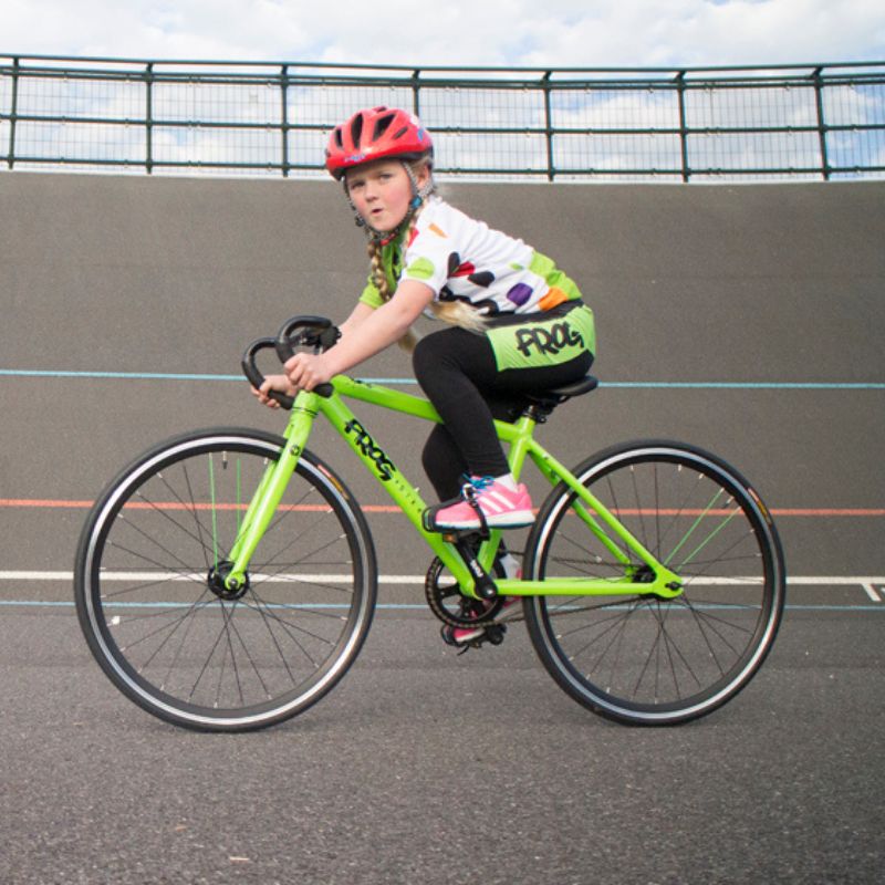 Child riding a Frog Track 67  green bicycle on an outdoor track