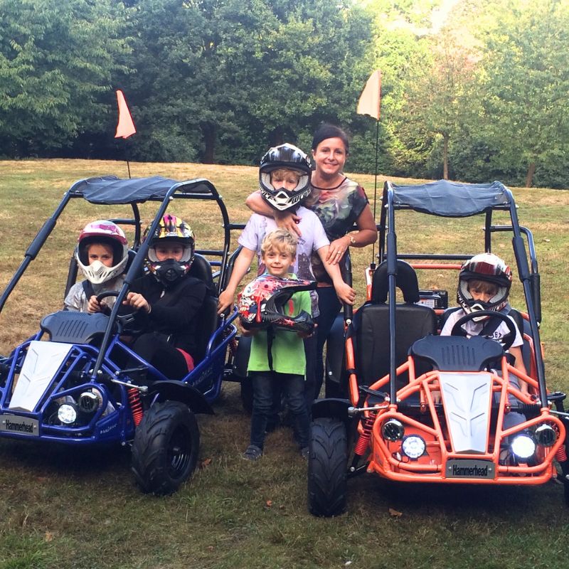 Family with children in go-karts on a grassy field