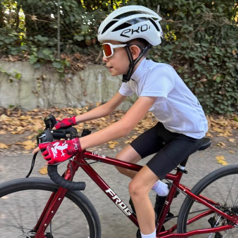 kid riding a frog road 67 bike with white helmet and grass background