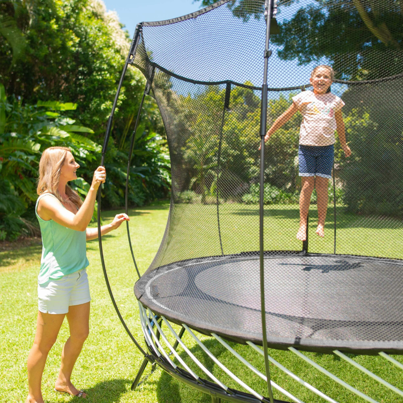 Springfree 8ft Compact Round Trampoline with safety enclosure – child bouncing while parent supervises in a sunny garden
