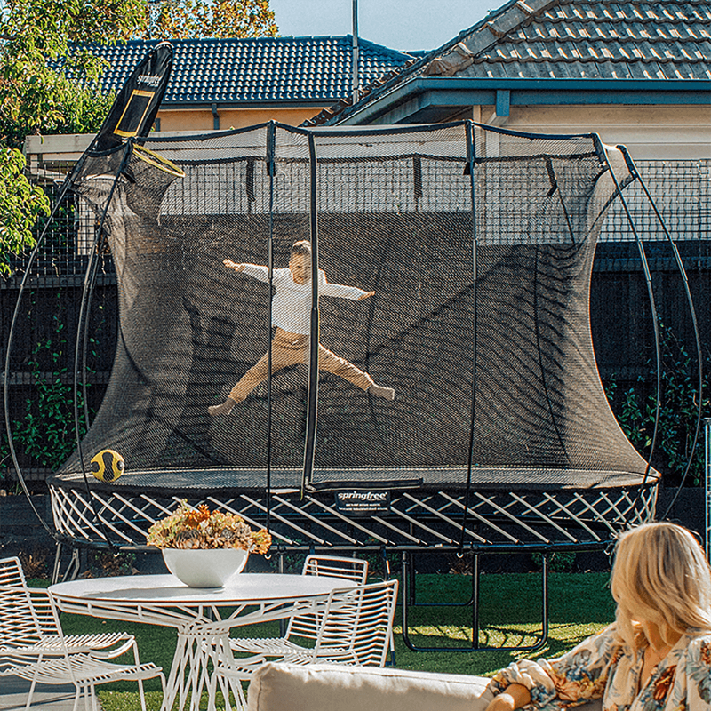 Springfree® 8ft x 11ft Oval Trampoline at the garden with kid enjoying jumping